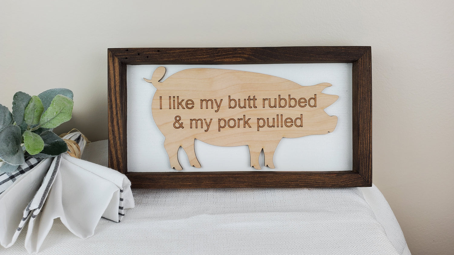 Fun BarBQ sign with the message engraved on a wooden pig outline. The handmade, dark stained frame is wide enough to sit on it's own or to hang on a wall. I like my butt rubbed and my pork pulled is the funny message referencing BarBQ pork