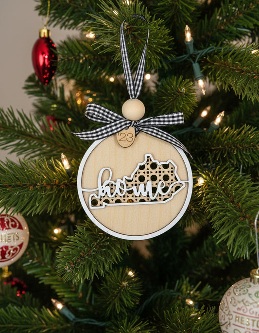 Decorative Kentucky ornament with 'home' and state outline on a Christmas tree.