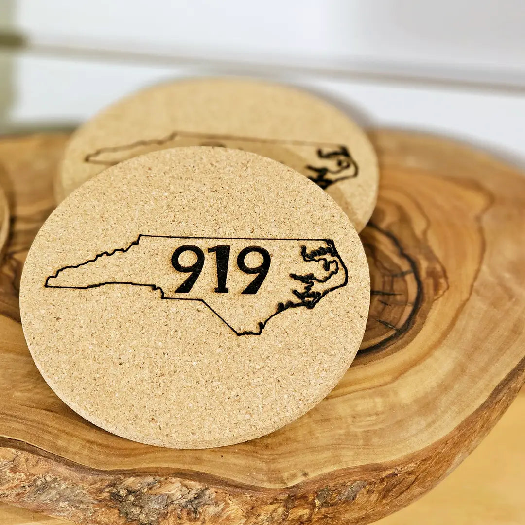 Custom Cork coaster with North Carolina outline and '919' on a wooden surface