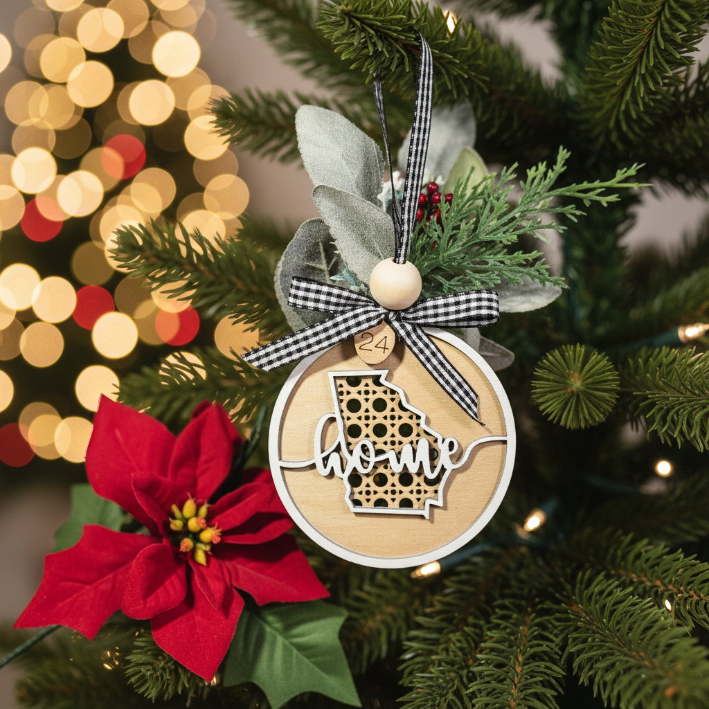 Decorative ornament with 'home' text, poinsettia flower, and greenery hanging from a holiday tree