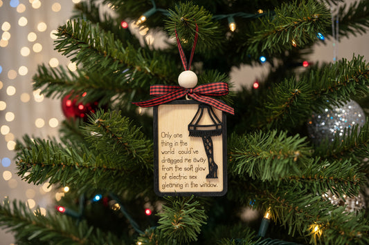 Leg lamp Christmas ornament with a Ralphie quote engraved on the front of the 2-layer ornament, on a tree with lights in the background