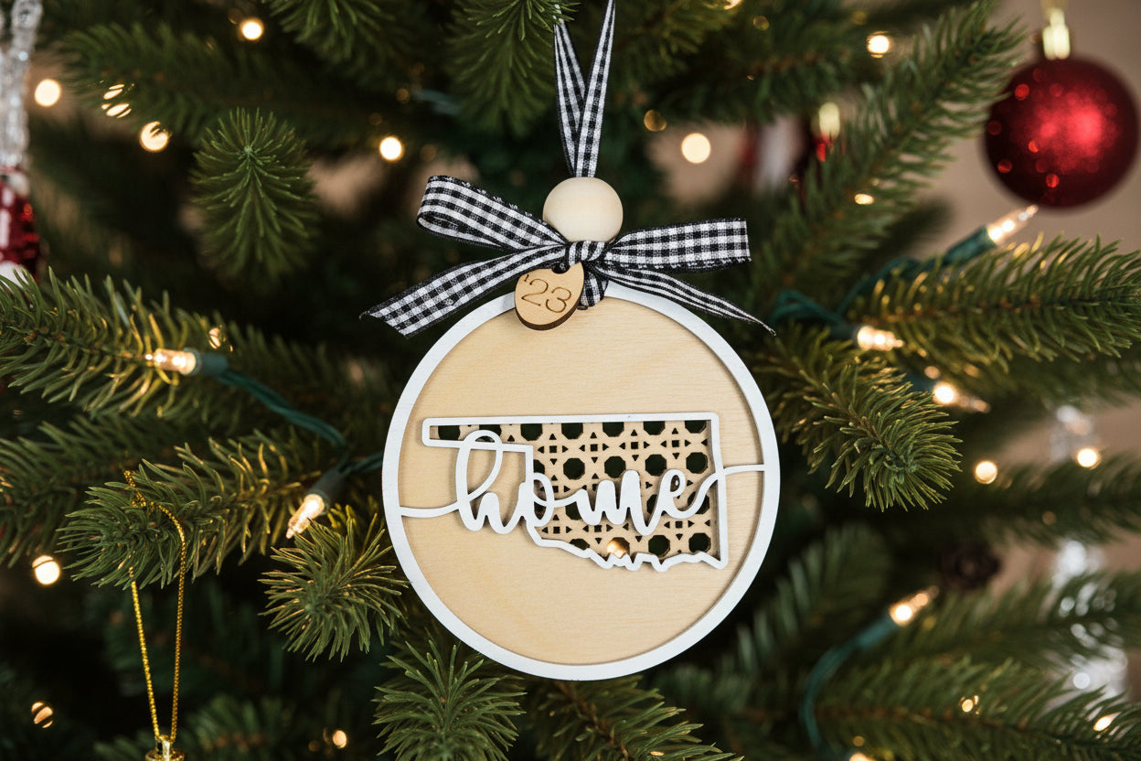 Decorative Christmas ornament shaped like the state of Oklahoma on a tree with lights.