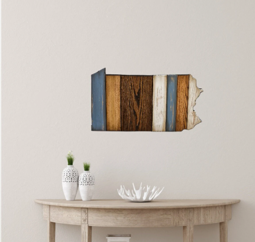 Wooden Pennsylvania wall art in the shape of a state above a wooden table with decor items.