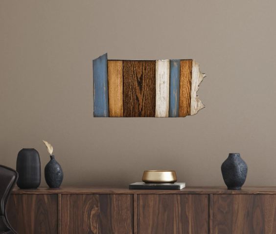 Wooden Pennsylvania wall art piece on a beige wall above a wooden console table with decorative items.