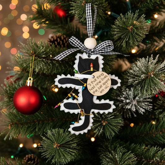 Decorative  fried cat Christmas ornament on a branch with pine cones and red ornaments.