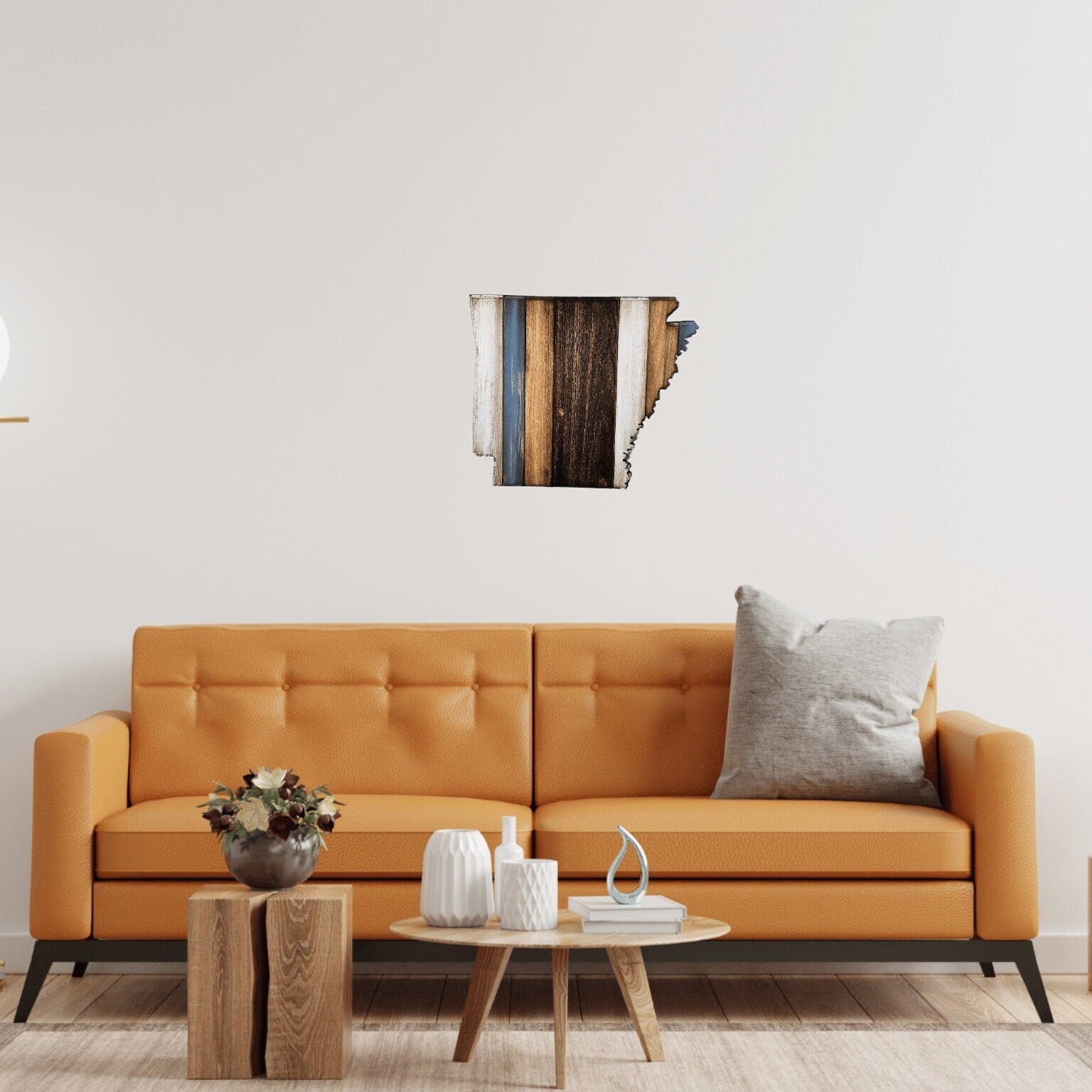 Orange sofa in a living room with a rustic, handmade Arkansas wall art piece and decorative items. 