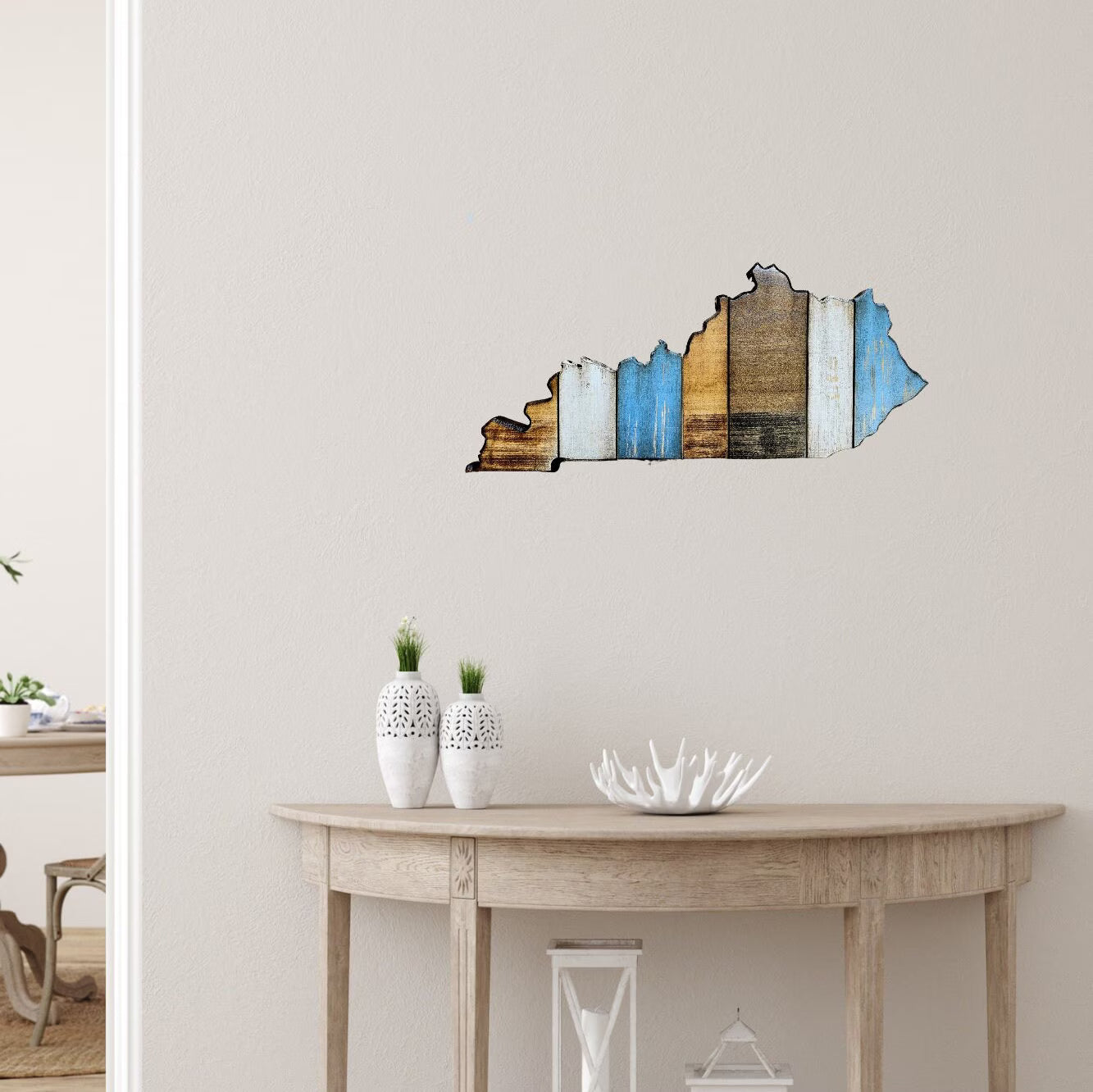 Kentucky wall art on a plain wall above a wooden table with decorative items.