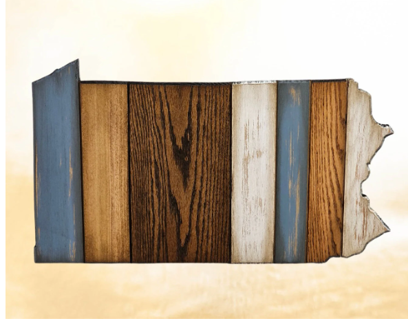 A handmade wooden cutout in the shape of the state of Pennsylvania, with a distressed finish and a wire hanger on the back.