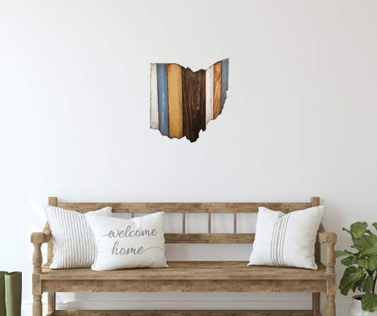 Handmade cut-out in the shape of the state of Ohio hanging over a wood bench with pillows.