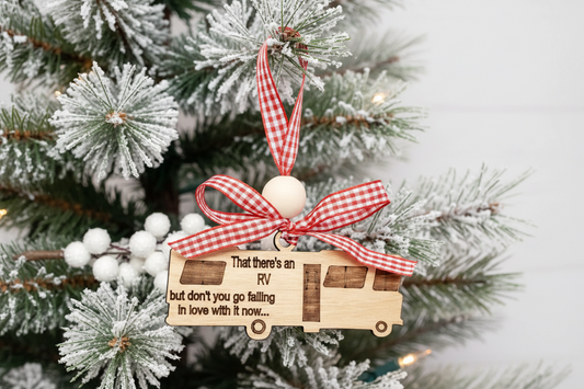 Wooden ornament shaped like a RV, with a red checkered ribbon on a Christmas tree.