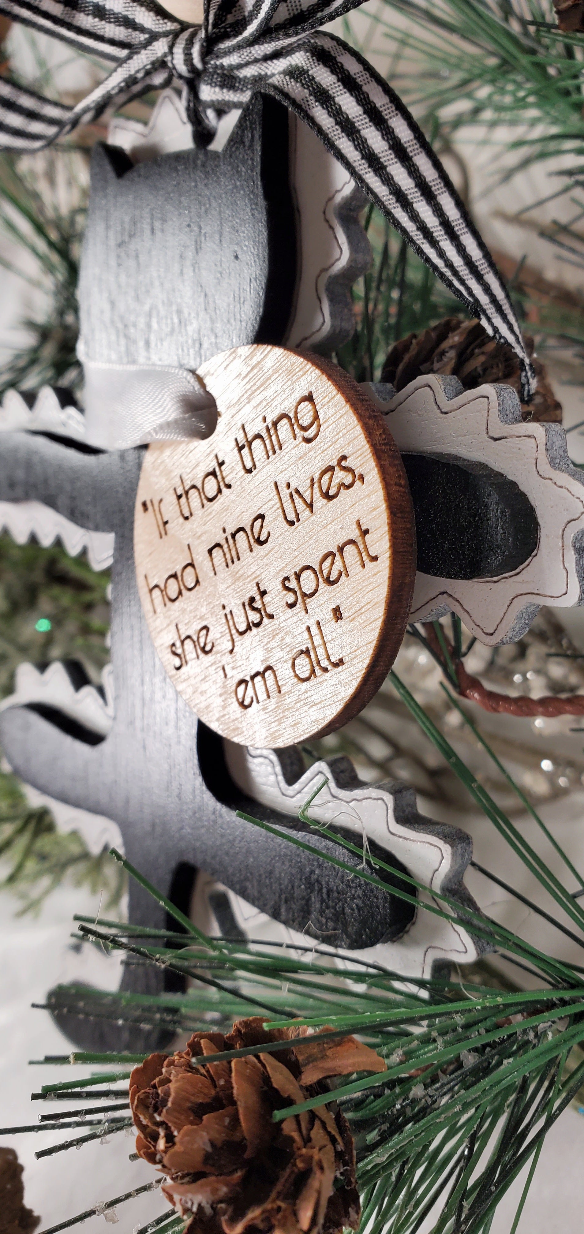 Close-up of fried cat ornament showing laser-engraved detail and quote tag "If that thing had nine lives"

