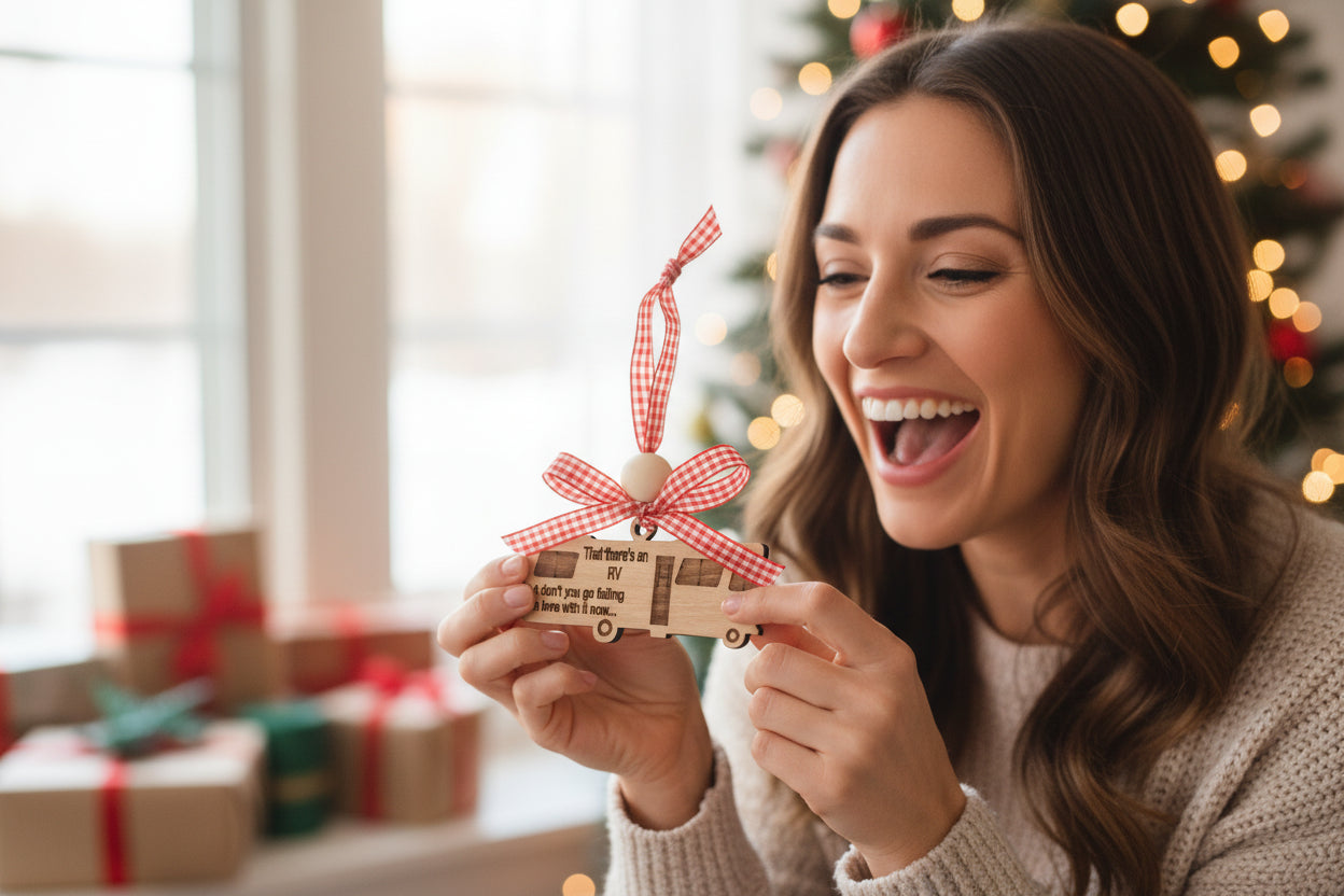 A wooden ornament shaped like an RV with a red and white checkered bow on top, engraved text 'That there's an RV but don't you go falling in love with it now.